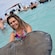 A woman standing in water with her arms cradled under a stingray